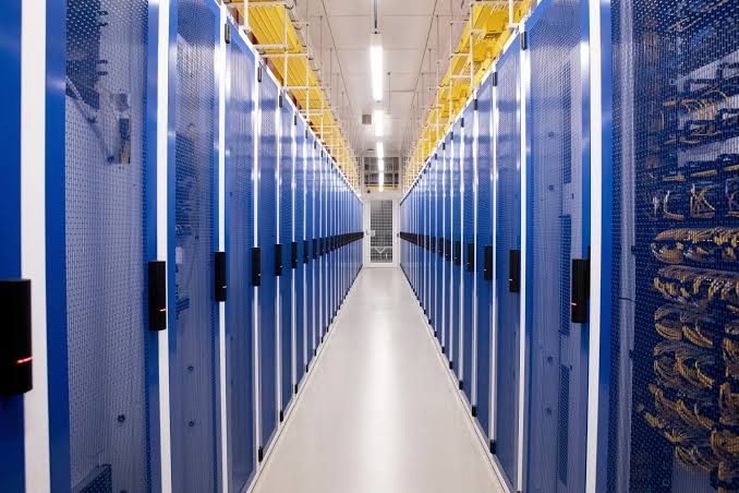 Data hall aisle lined with blue server cages and overhead cable trays